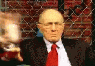Man in Suit Sitting in Front of Chain Link Fence