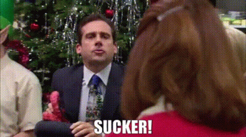 Man In Suit Sitting In Front Of Christmas Tree With Woman Behind GIF
