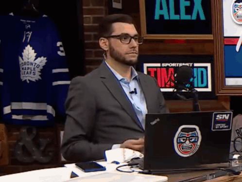 Man in Suit Sitting in Front of Laptop Saying Alex