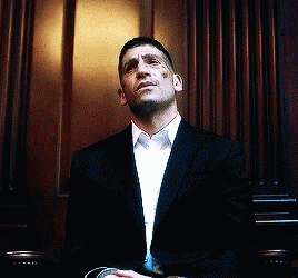 Man in Suit Sitting in Front of Wooden Wall