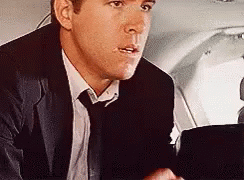 Man In Suit Sitting In Plane Back Seat GIF