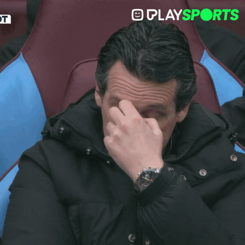 Man In Suit Sitting In Stadium In Front Of Play Sports Screen GIF