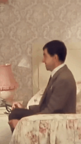 Man In Suit Sitting On Bed GIF