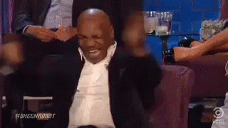 Man in Suit Sitting on Couch Arms Outstretched Smiling