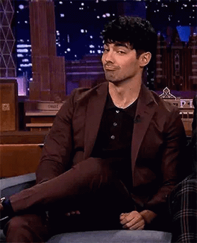 Man In Suit Sitting On Couch Crossed Leg Smiling GIF