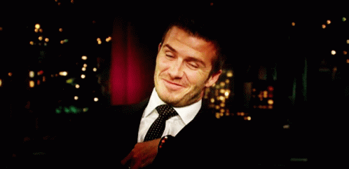Man in Suit Smiling Before Red Curtain