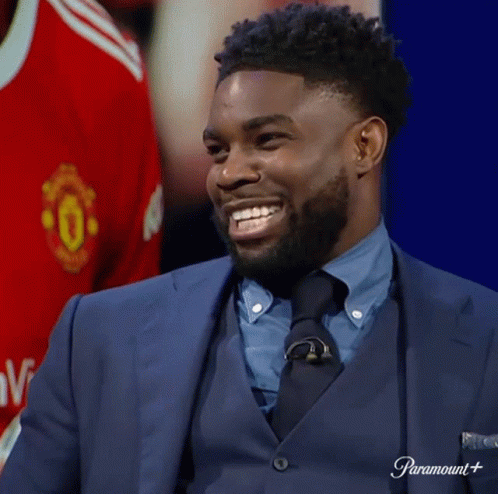 Man In Suit Smiling Beside Manchester United Shirt GIF