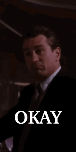 Man in Suit Smiling Holding Glass Saying Okay