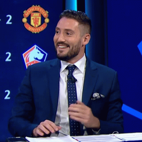 Man in Suit Smiling in Front of Manchester United Sign