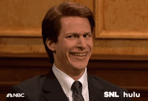 Man In Suit Smiling In Front Of SNL Hulu Sign GIF