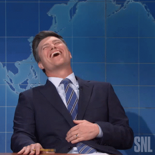 Man in Suit Smiling in Front of SNL Logo
