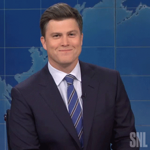 Man in Suit Smiling in Front of SNL Sign