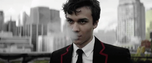 Man in Suit Smoking Cigarette in Front of City