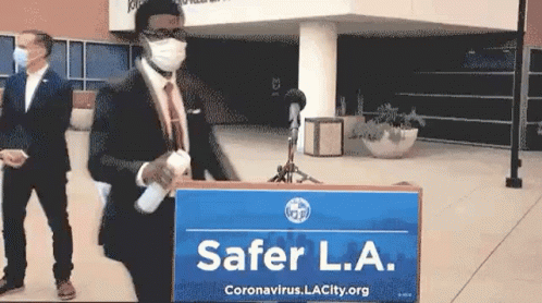 Man in Suit Standing Before Safer L.A. Sign