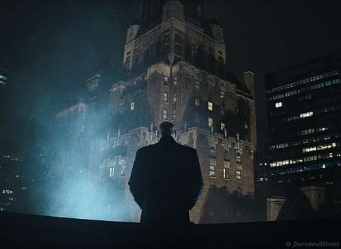 Man in Suit Standing in Front of Building at Night