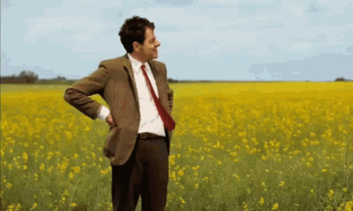 Man In Suit Standing In Yellow Flowers GIF