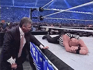 Man In Suit Standing Next To Wrestler On Floor GIF
