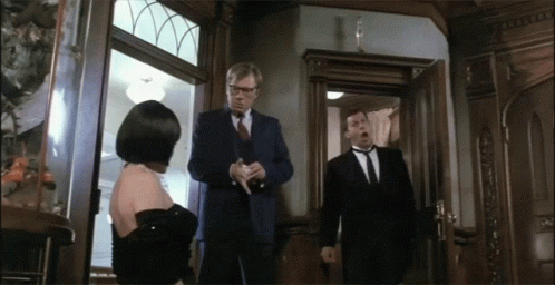 Man In Suit Stands In Front Of Woman In Black Dress GIF