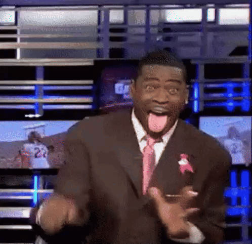 Man in Suit Sticking Tongue Out in Front of TV