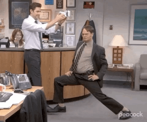 Man in Suit Stretching in Office While Another Takes Picture
