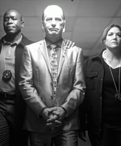 Man in Suit Surrounded by Police and Woman with Star Necklace