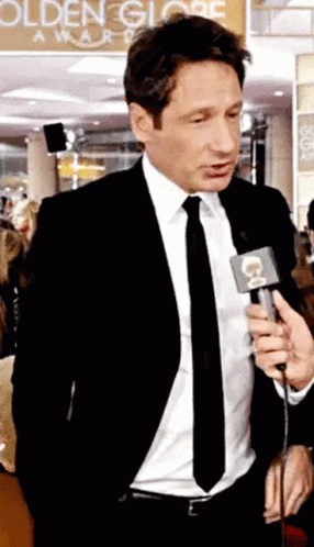 Man in Suit Talking Into Microphone to Crowd