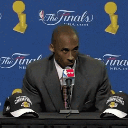 Man in Suit Talking Into Microphone What's There to Be Happy About