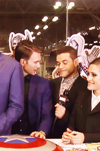 Man in Suit Talking Into Microphone Woman Looking On