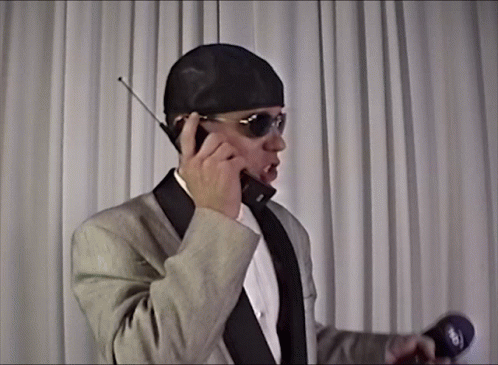 Man in Suit Talking on Cell Phone Holding Microphone Saying Sky