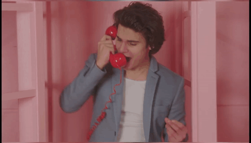 Man in Suit Talking on Red Telephone Saying More