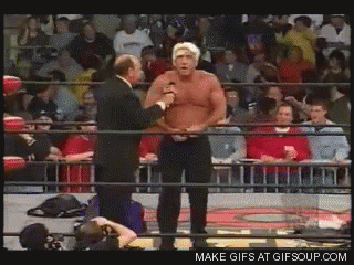 Man In Suit Talking To Another In Wrestling Ring With Crowd GIF