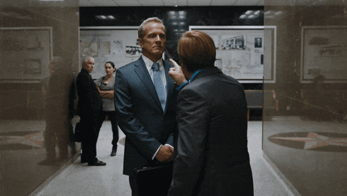 Man in Suit Talking to Another Man