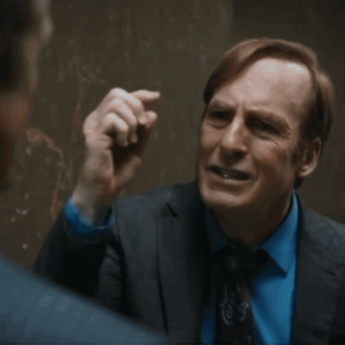 Man in Suit Talking to Another Man in Dark Room