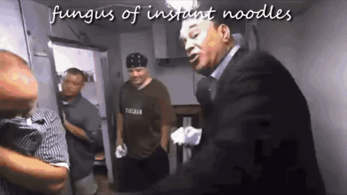 Man in Suit Talking to Man in Chicago Shirt in Kitchen