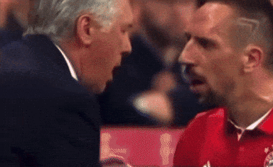 Man in Suit Talking to Man in Red Shirt