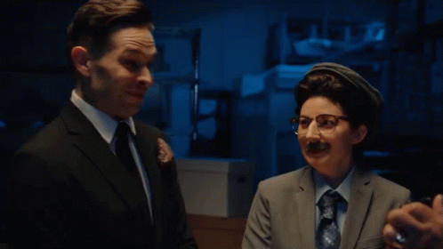 Man in Suit Talking to Woman in Glasses
