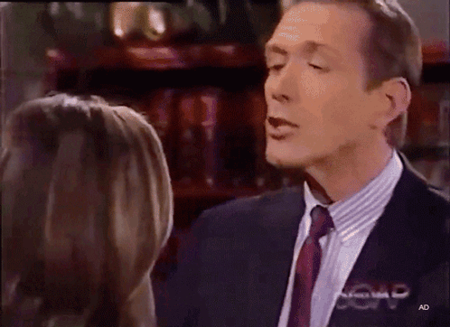 Man in Suit Talking to Woman With AD Letters