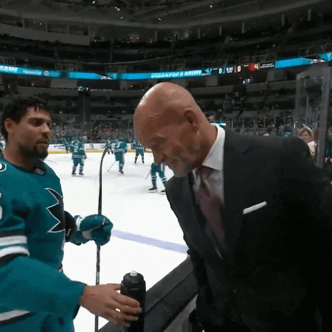 Man in Suit Talks to Man in Sharks Jersey