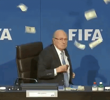 Man in Suit Tie at Desk FIFA Sign
