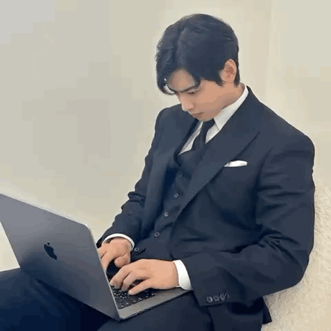 Man in Suit Typing on Laptop
