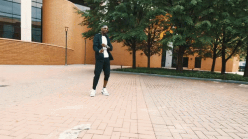 Man In Suit Walking Down Brick Street GIF