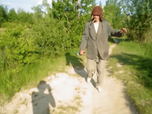 Man in Suit Walking Down Dirt Path Smoking Cigarette