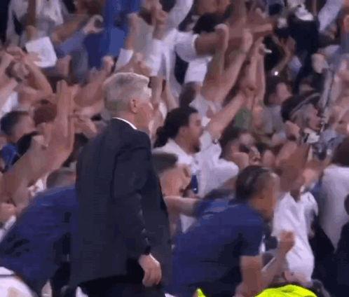 Man in Suit Walking Through Crowd at Basketball Game