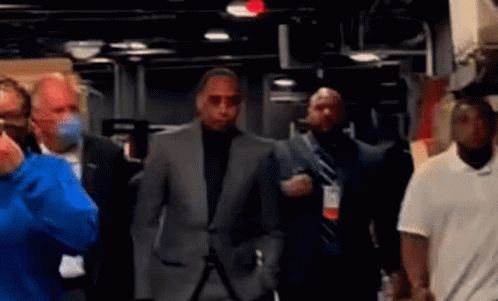 Man in Suit Walking Through Masked Crowd