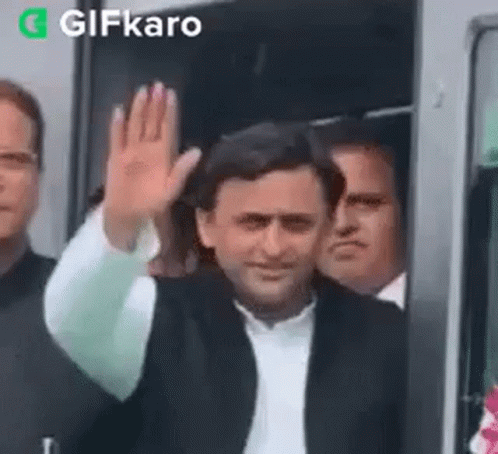 Man In Suit Waving In Front Of Bus GIF