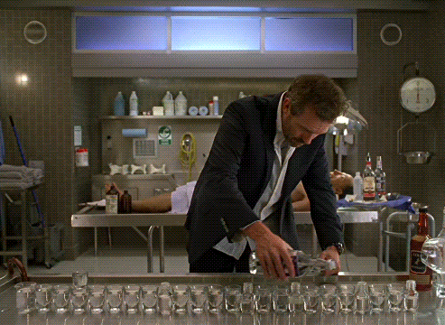 Man In Suit With Shot Glasses In Lab GIF
