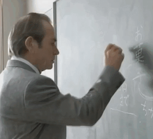 Man in Suit Writing Chinese Characters on Whiteboard