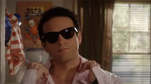 Man in Sunglasses Adjusting White Shirt