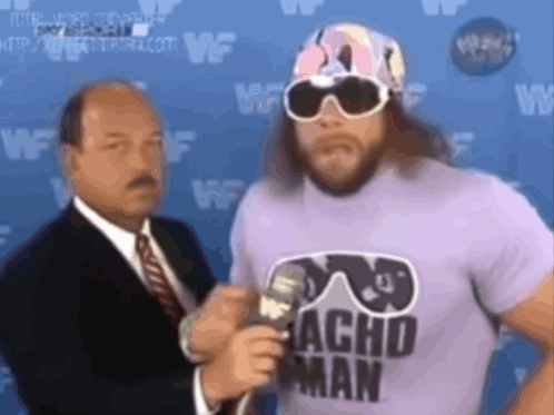 Man In Sunglasses And Acho Man Shirt Talks Into Microphone GIF