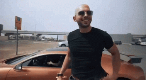Man in Sunglasses and Black Shirt Next to Orange Car